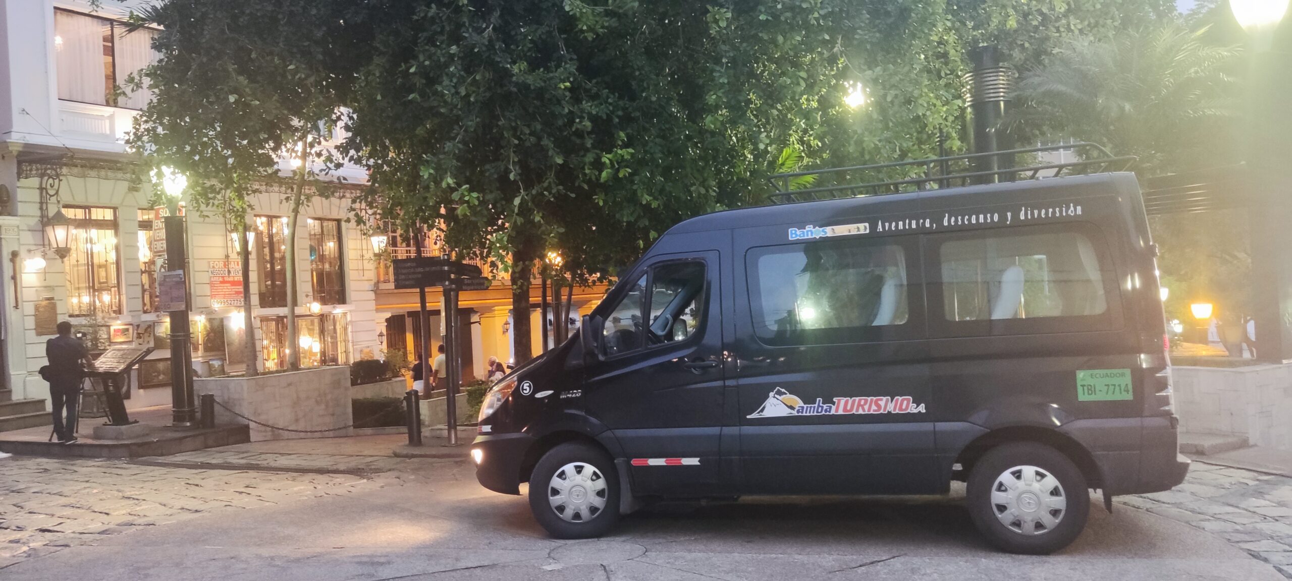 Vehículo de Ambaturismo C.A. brindando transporte turístico en el centro histórico de una ciudad del Ecuador durante la noche.
